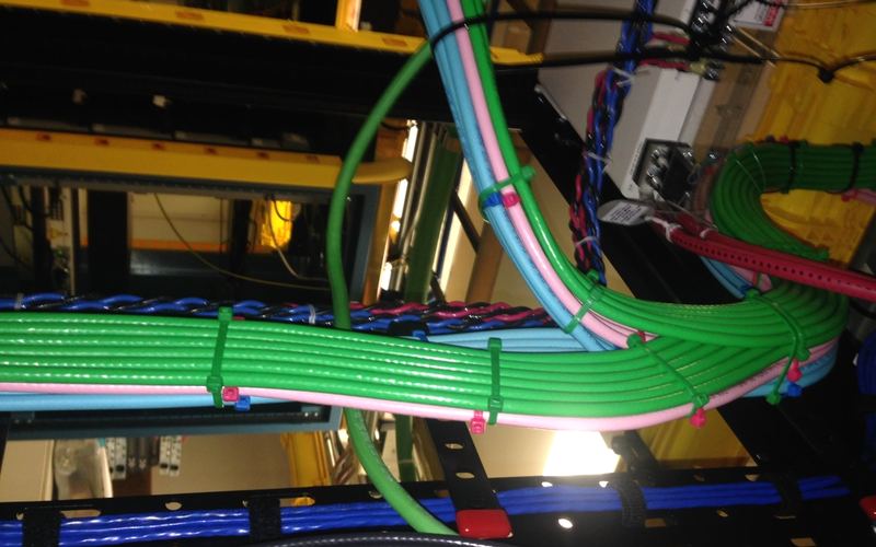 Bundled network and ground cables dressed and tied along a cable runway