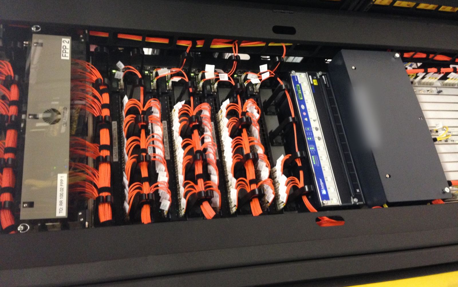 Fiber patch panels with dressed orange fiber jumpers in a telecom rack